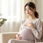 妊娠中の女性がリビングで深呼吸をして気持ちを落ち着けているシーン｜妊娠中のイライラ・情緒不安定のイメージ