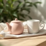 窓辺のテーブルに置かれたマグカップとティーポットのイメージ|妊娠中のカフェインとの付き合い方